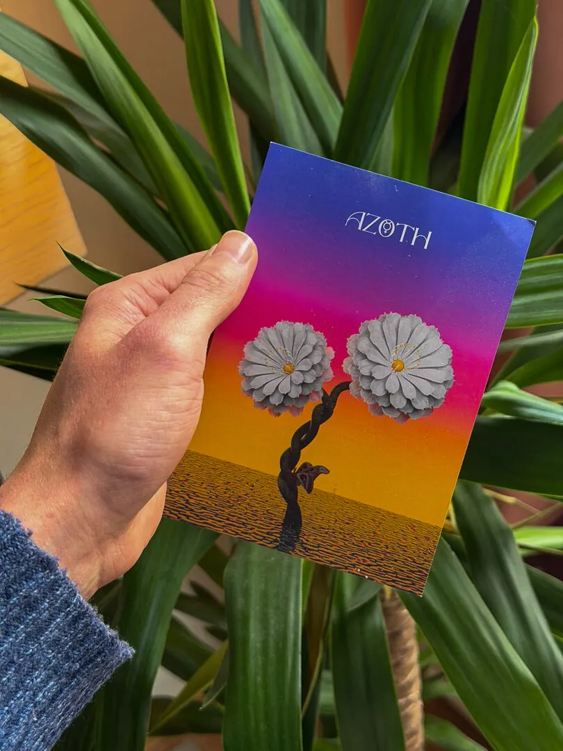 A hand holding an AZOTH flyer with two chrome flowers