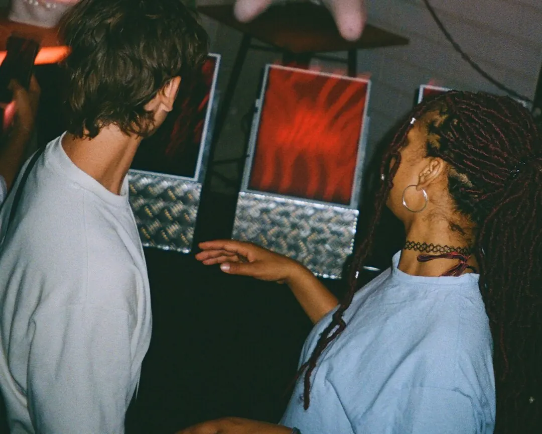Two people at a party in front of glowing red artworks