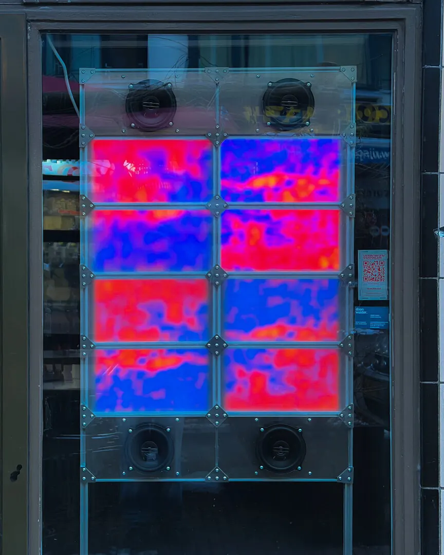 The installation in a shop window: eight translucent panels glowing in red and blue infrared colours