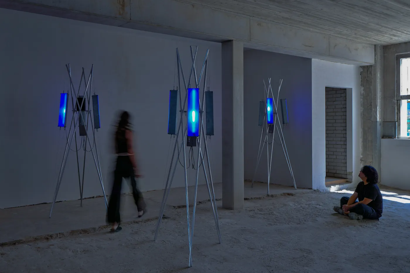 Antenna sculptures with blue light tubes in a concrete space